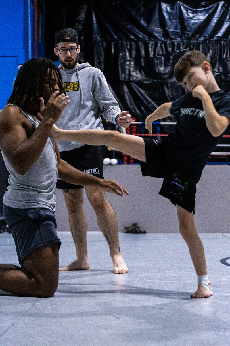 Student kicking into a coach's hand while another coach watches